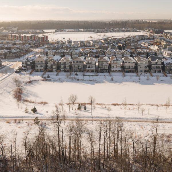 Wide aerial view of snow covered residential areas and open fields in Trumpeter by Big Lake, Edmonton, Alberta.