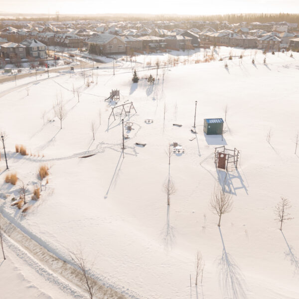 Aerial view of a snow covered park with pathways and playground structures in Trumpeter by Big Lake, Edmonton, Alberta.