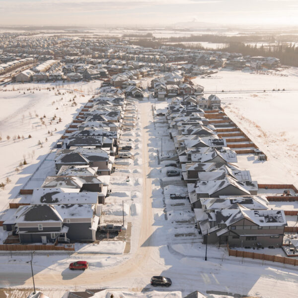 Aerial view of homes bordering a snow covered open area in Trumpeter by Big Lake, Edmonton, Alberta.