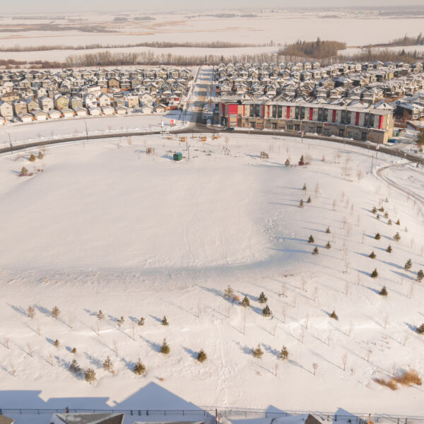 Aerial view of a large snow covered central park surrounded by homes in Trumpeter by Big Lake, Edmonton, Alberta.