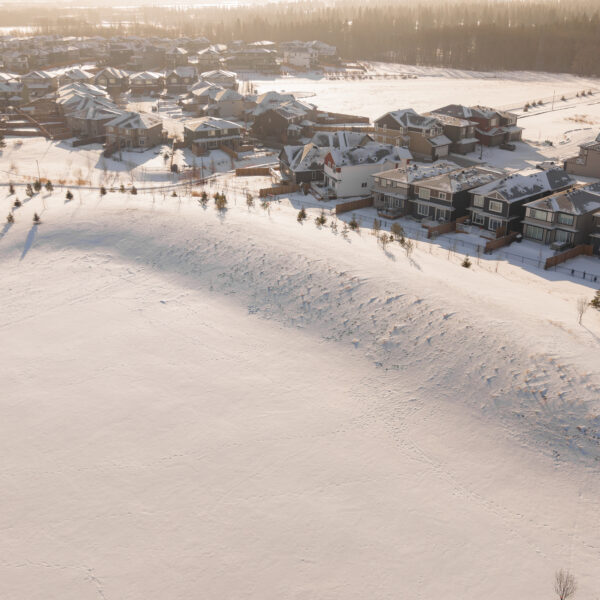 Aerial view of a snow covered open area behind a row of homes in Trumpeter by Big Lake, Edmonton, Alberta.